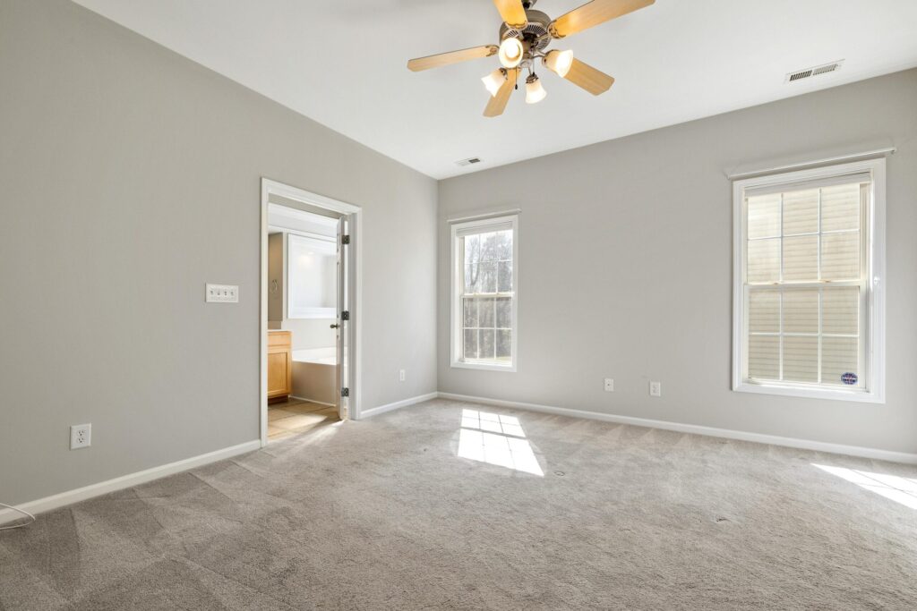 Empty bedroom featuring a ceiling fan and large windows